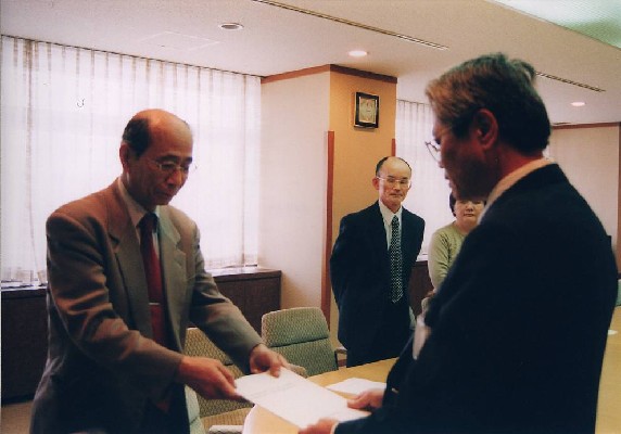 報告書を提出する中川委員長と報告を受ける市長代理の松本助役